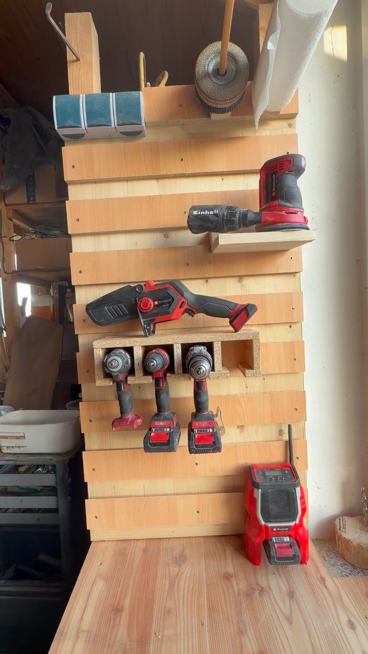 9 Tool Organization Wall Ideas for Garage and Shop 8 Wooden slat wall organizer holding red power drills and tools above a workbench.