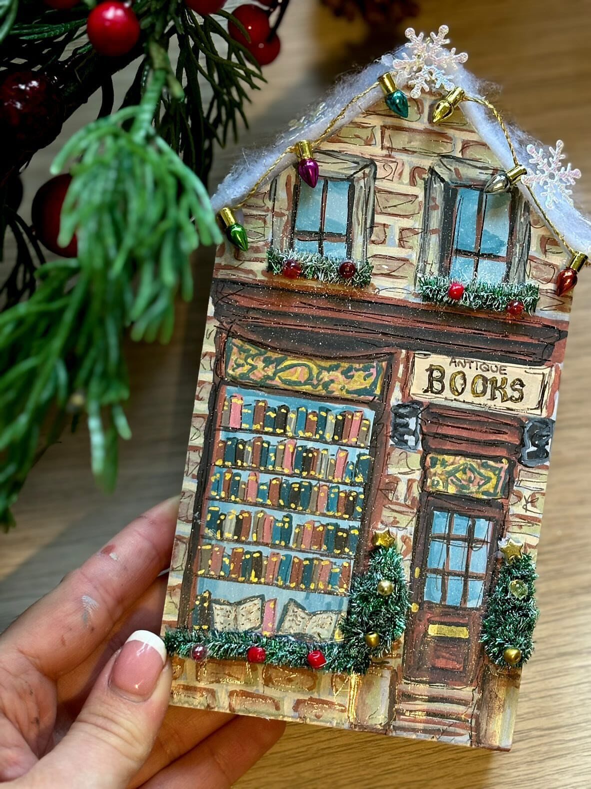 Handcrafted wooden miniature bookstore decorated with Christmas lights and fake snow.