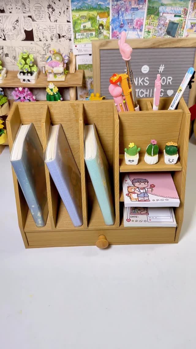 Wooden desk organizer holding notebooks and stationery on a white surface.