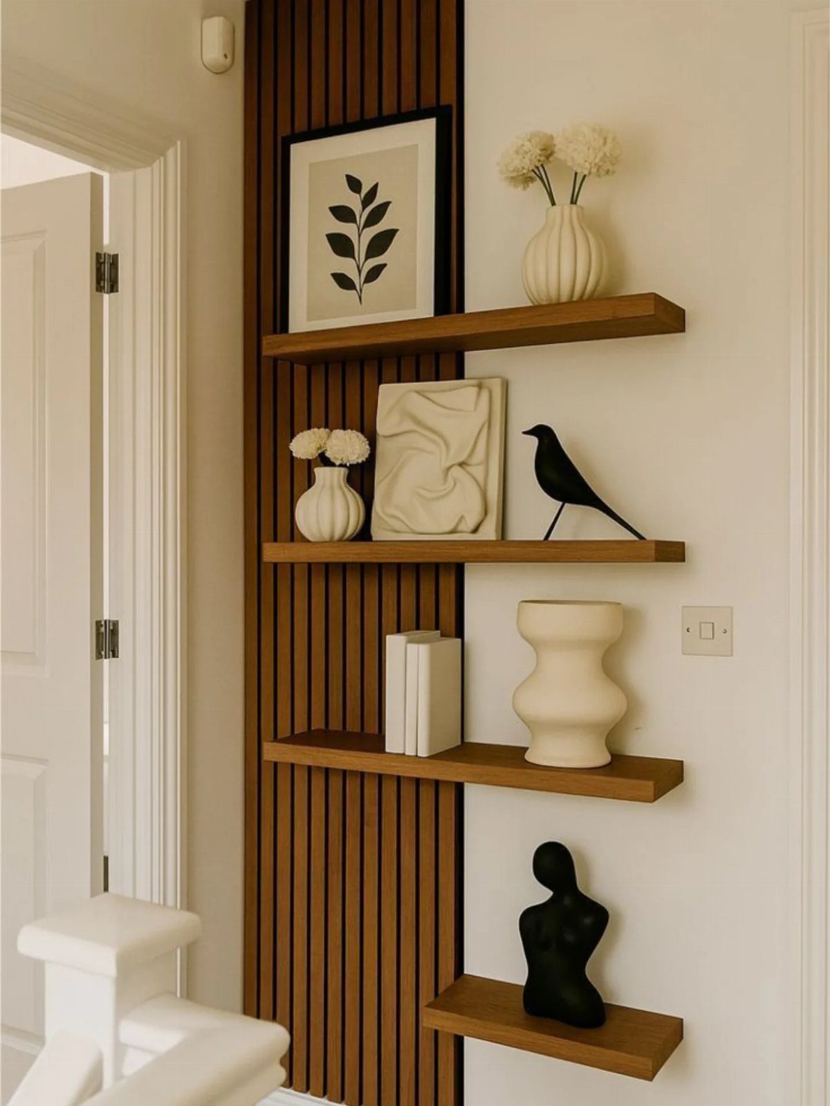 Floating wooden shelves on a white wall with a vertical wood slat accent panel.