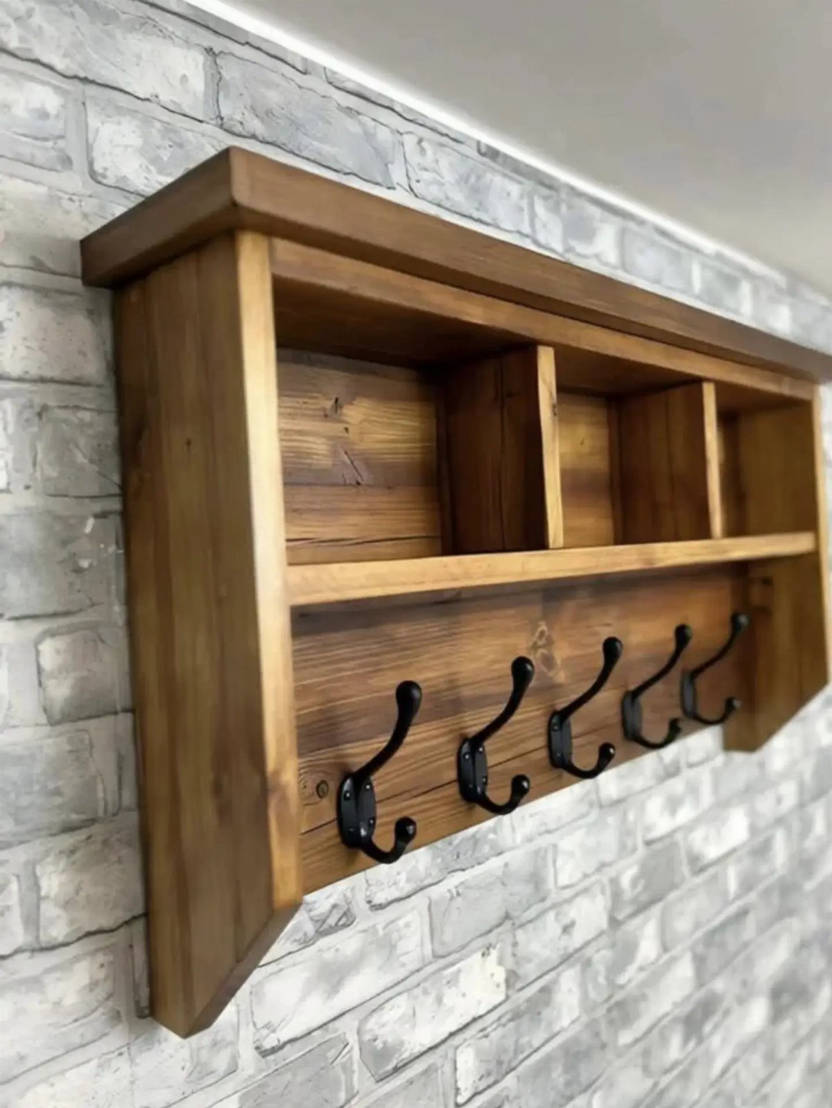 Wooden wall-mounted coat rack with black hooks and a top storage shelf.