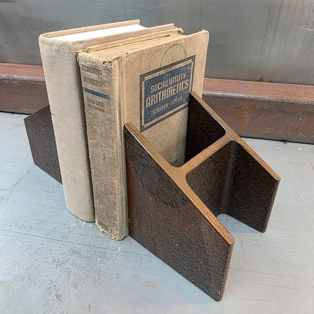 Old books held upright by a dark brown rusted metal geometric bookend