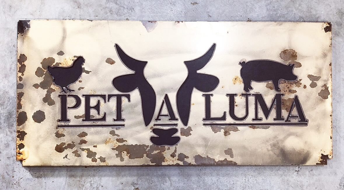 Metal custom sign with animal silhouettes and Petaluma text on a concrete wall