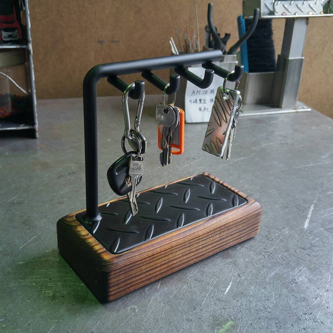 Black metal key holder with wooden base holding several sets of keys
