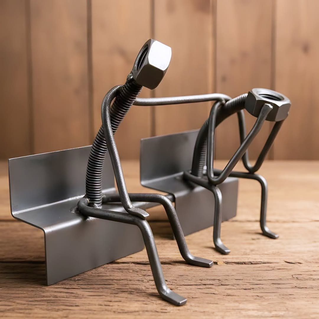 Welded metal figures made of nuts and bolts sitting on a wooden table.