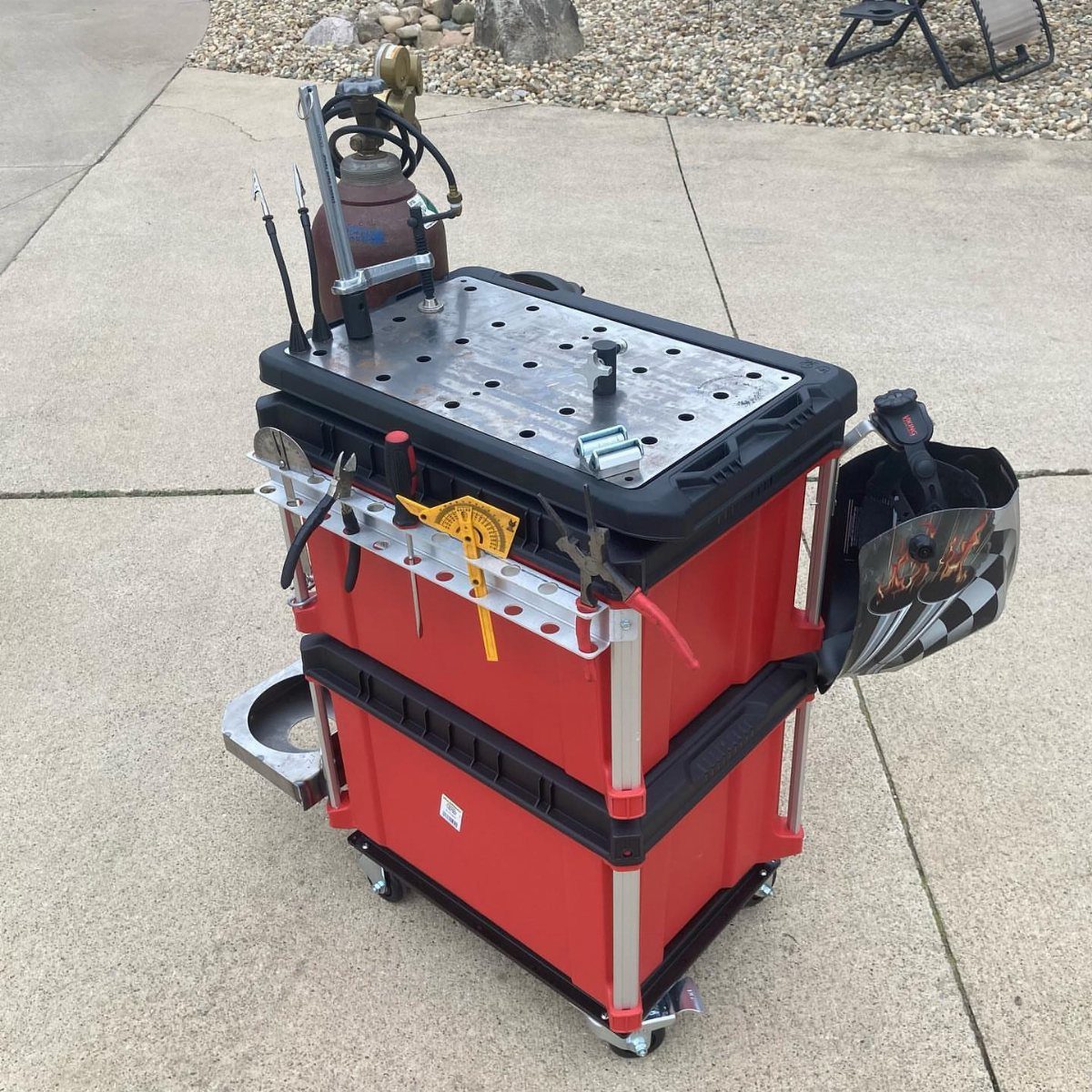 Red rolling tool cart with a perforated metal work surface and attached tools.
