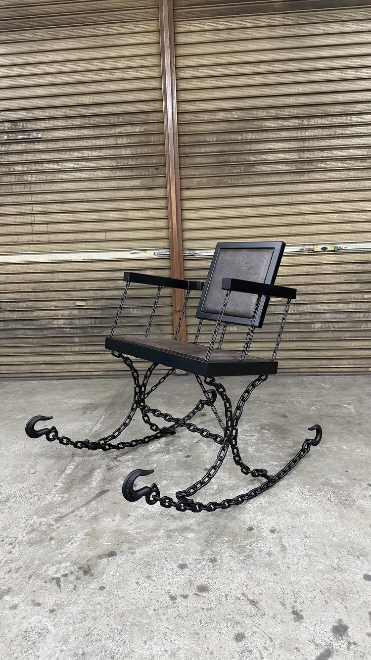 Black metal rocking chair with a base made of welded heavy chains and hooks.