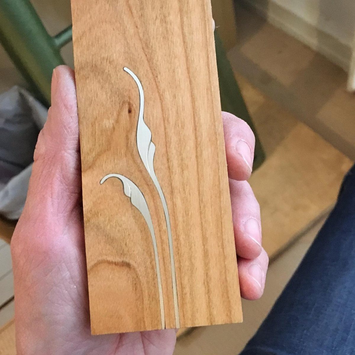 Wooden plank with a decorative silver metal inlay in a curved organic design.