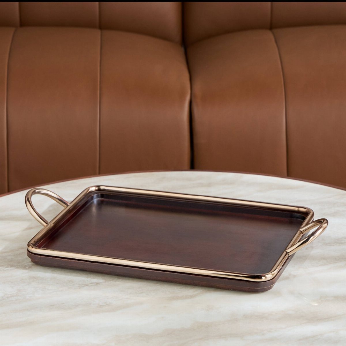 Rectangular dark wood serving tray with gold metal handles on a marble table