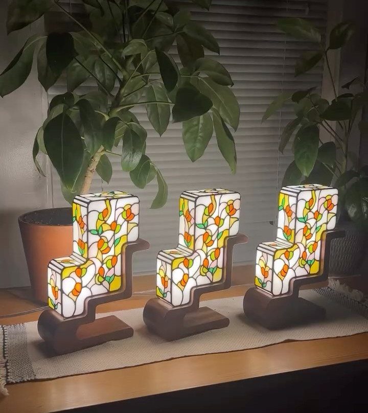 Three stained glass lamps with colorful floral patterns set in dark wooden bases.