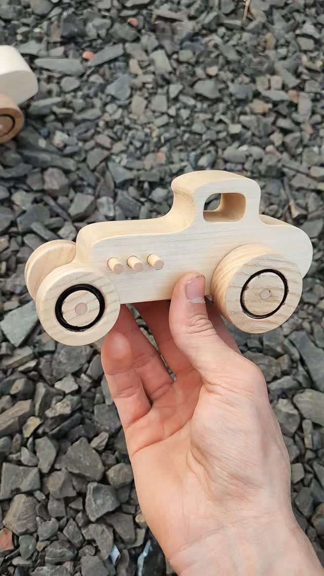 17 Wood Art Projects for Beginners and Weekend Makers 2 Small light-colored wooden toy car held by a hand over grey gravel.