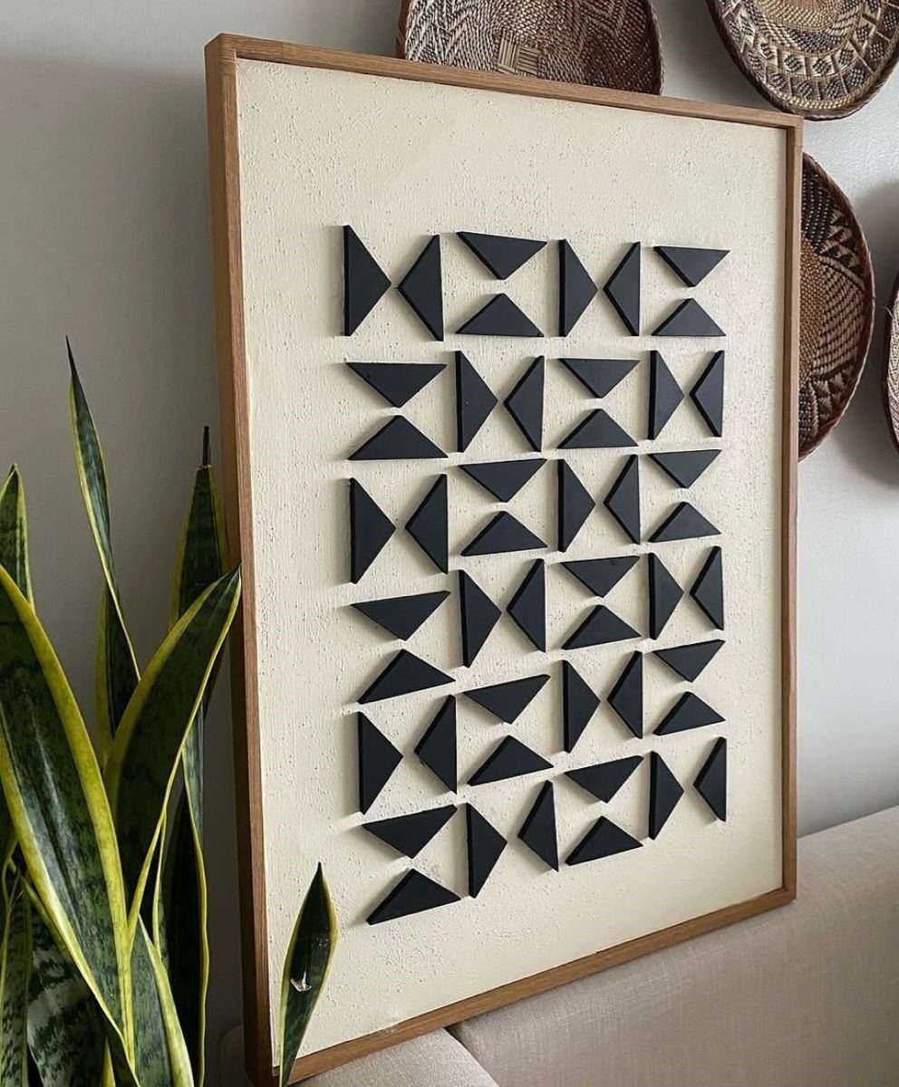 17 Wood Art Projects for Beginners and Weekend Makers 10 Modern geometric wall hanging with black wooden triangles on a textured white background.