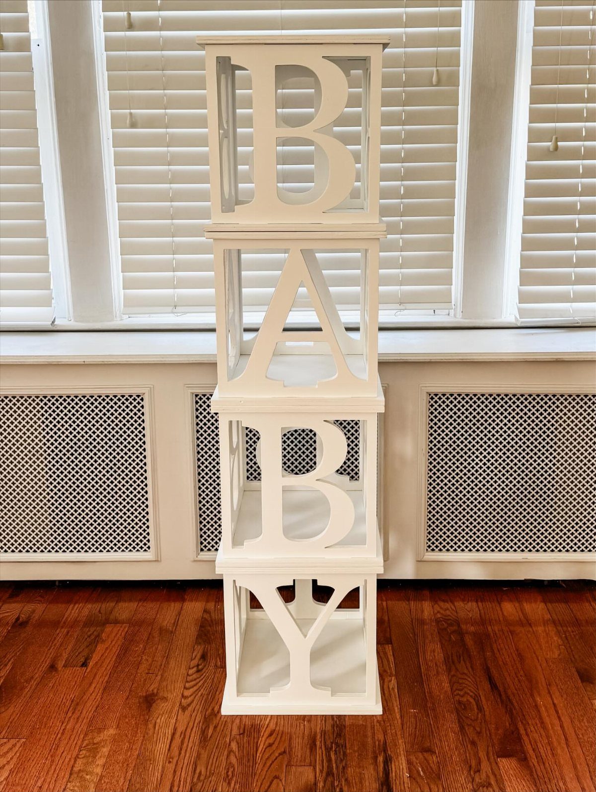 14 Wood Block Decorations for Every Season and Room 8 Stacked white wooden blocks spelling BABY on a brown hardwood floor.
