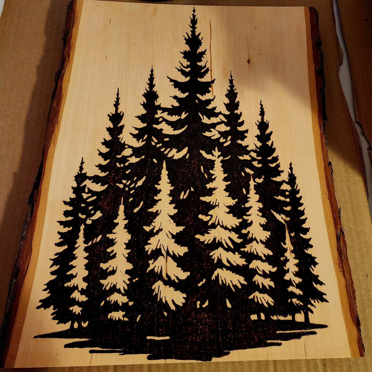 Wood Burned Pine Trees: 4 Ideas for Pyrography 1 Wood burned pine trees on a light natural wood slab with live edges.