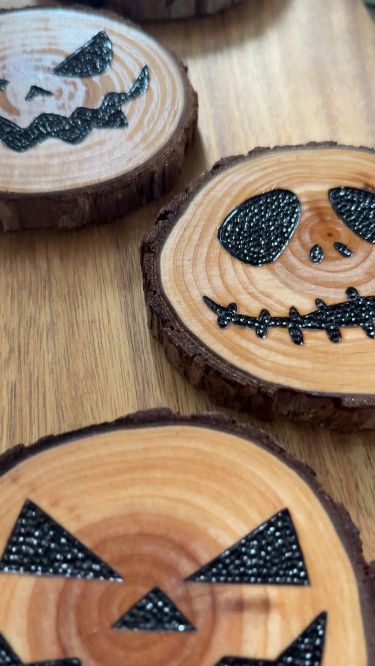 9 Wood Burning Images for Spoons, Plaques and Coasters 5 Wooden slices with burned jack-o'-lantern faces resting on a light wood surface.