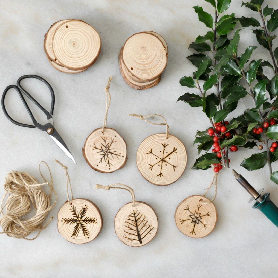 Wood Burning Ornaments: 8 Ideas for Christmas 3 Birch wood slice ornaments with burned snowflake and tree designs and crafting tools.