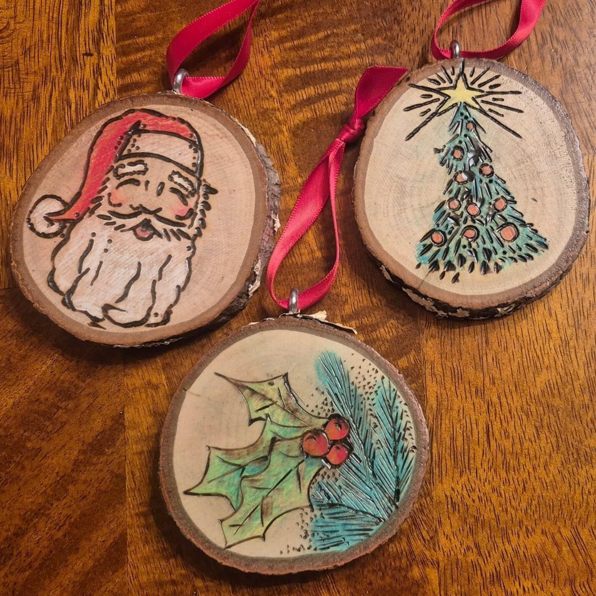 Wood Burning Ornaments: 8 Ideas for Christmas 5 Three wood slice ornaments with burned designs of Santa, a tree, and holly.
