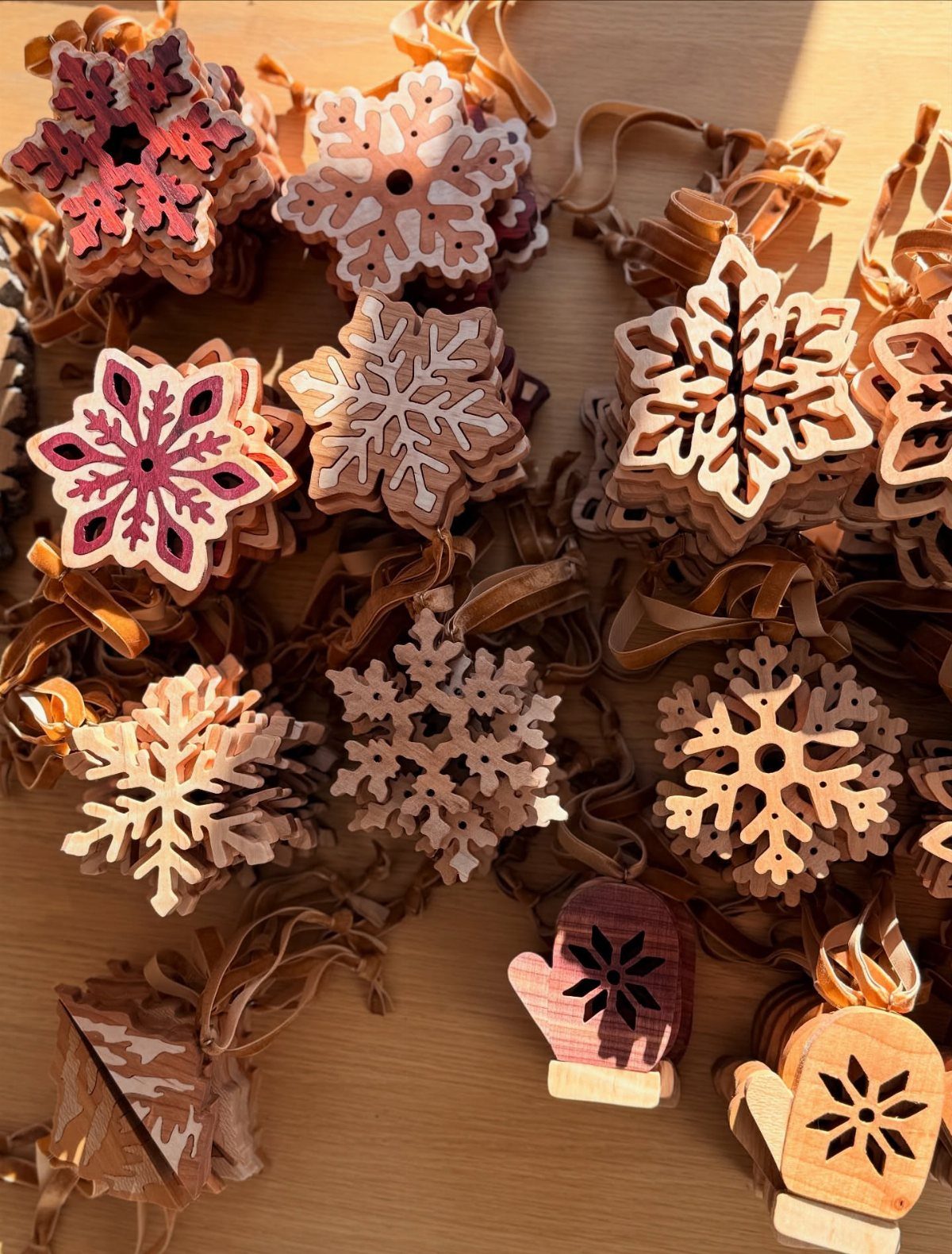 Wood Burning Ornaments: 8 Ideas for Christmas 8 Wooden snowflake and mitten ornaments with wood-burned designs on a wooden table