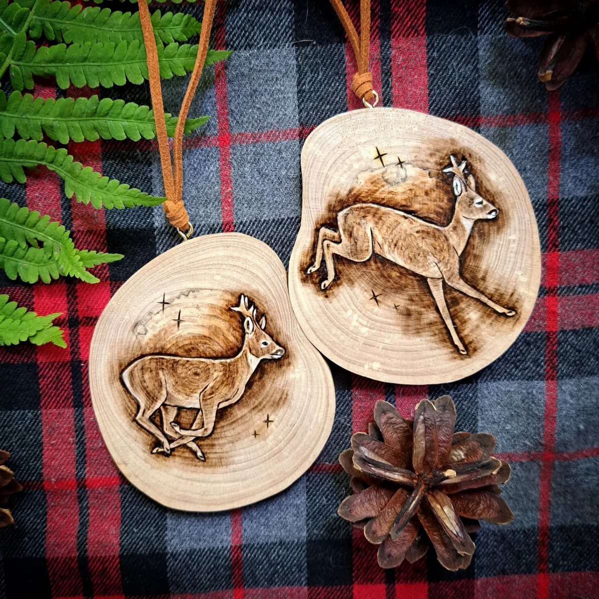 Wood Burning Ornaments: 8 Ideas for Christmas 7 Two wood slice ornaments with wood burned deer designs on plaid fabric.