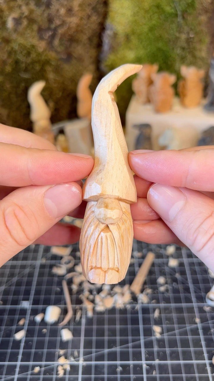 Hand-carved wooden gnome figurine with a long beard and tall curved hat.