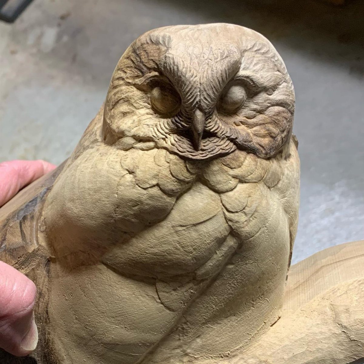 Handcrafted wooden owl figurine with detailed carved feathers and closed eyes.