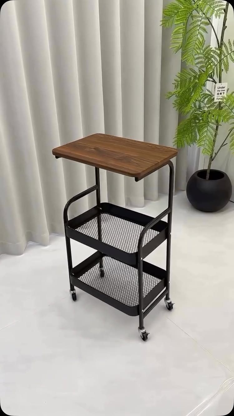 Rolling cart with a wooden top and black mesh shelves on caster wheels.