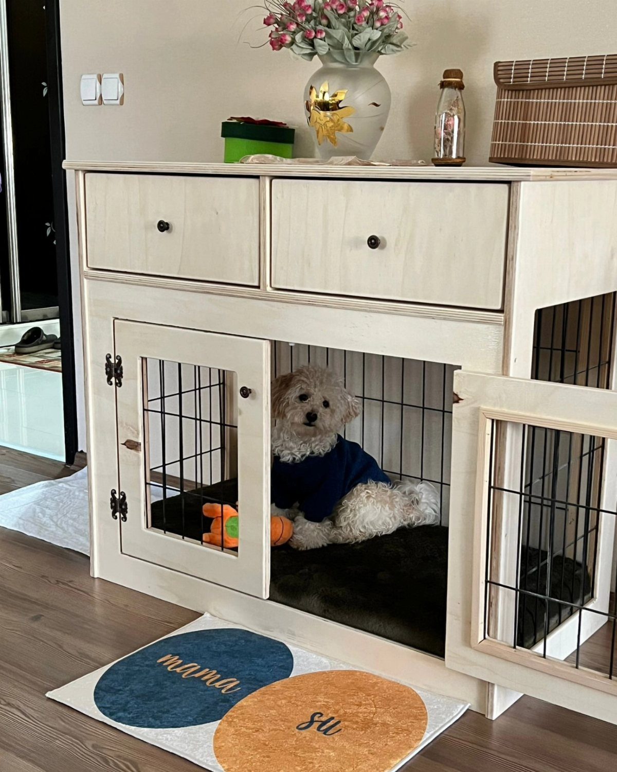 Small white dog in a wooden pet bed integrated into a dresser.