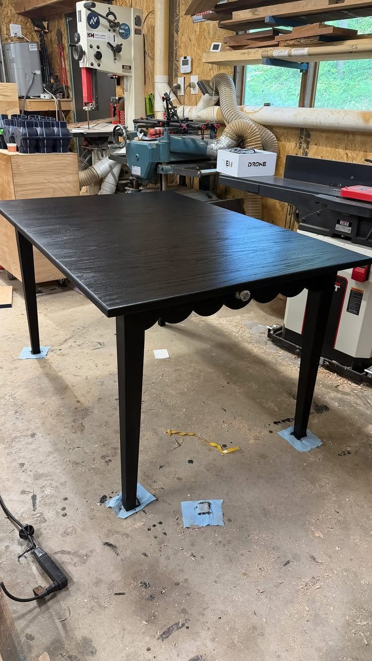 Black stained wooden table with scalloped edges in a professional woodworking shop