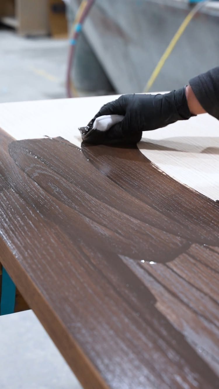 Wood Grain Stain: 8 Ideas for Color and Application 6 Hand in black glove applying dark brown stain to a wooden board