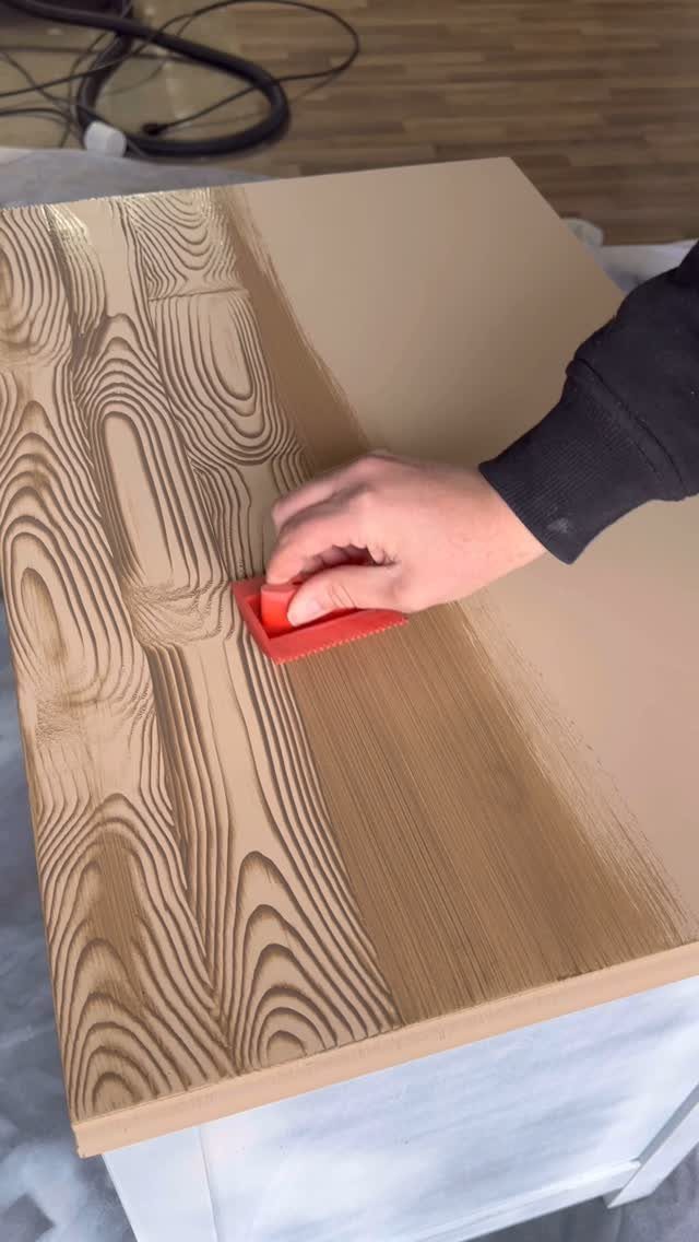 Wood Grain Stain: 8 Ideas for Color and Application 8 Hand applying brown wood grain stain to a board using a red sponge.