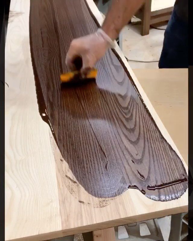 Wood Grain Stain: 8 Ideas for Color and Application 5 Hand applying dark brown stain to a light wooden board with a yellow sponge.