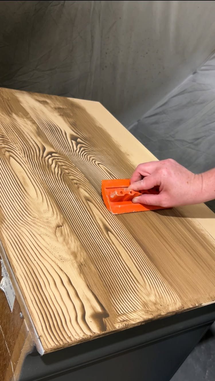 Wood Grain Stain: 8 Ideas for Color and Application 3 Hand using an orange rubber graining tool to create faux wood grain on a table.