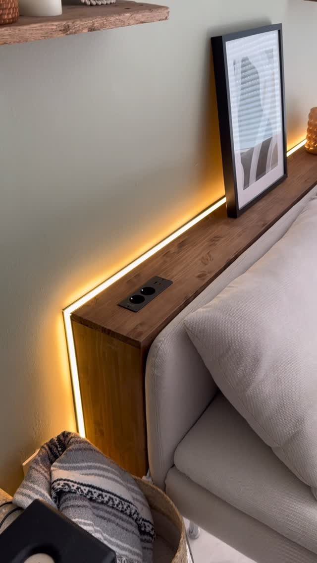 Wooden wall shelf with LED lighting and power outlet behind a grey sofa