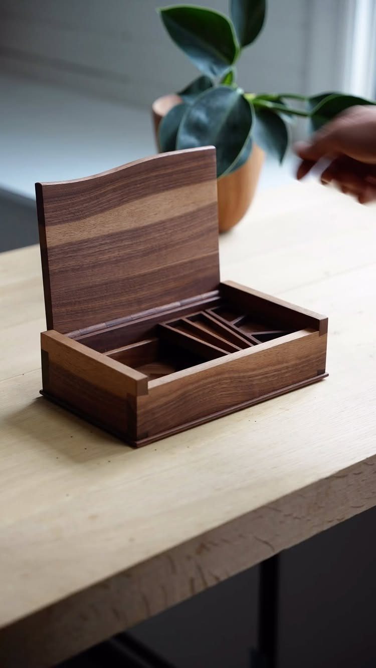 Small wooden jewelry box with a curved lid and compartments on a table