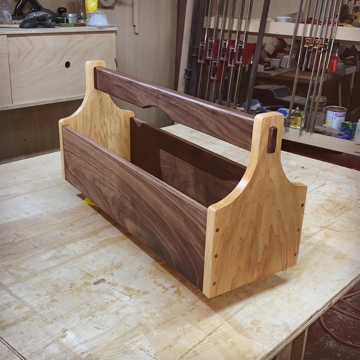 Wooden tool caddy with a handle resting on a workshop workbench.