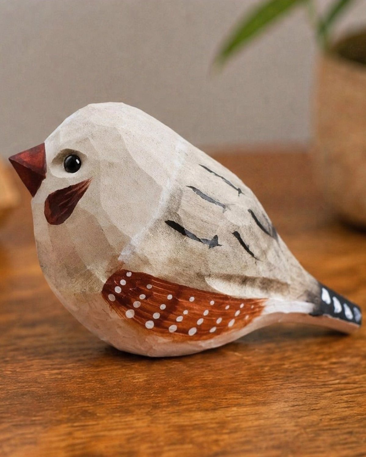 Hand-carved wooden bird figurine with painted details resting on a wooden table.