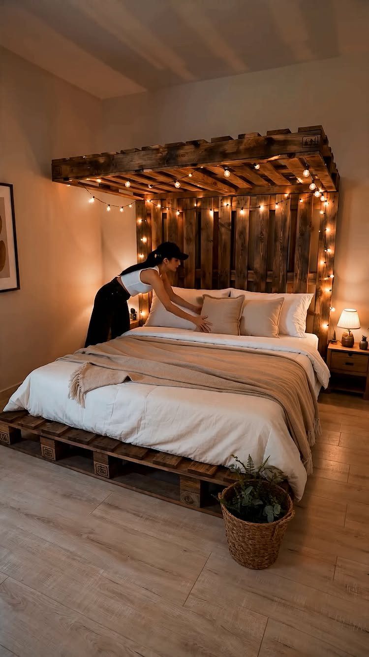 Wooden pallet bed frame with a rustic canopy and warm string lights.
