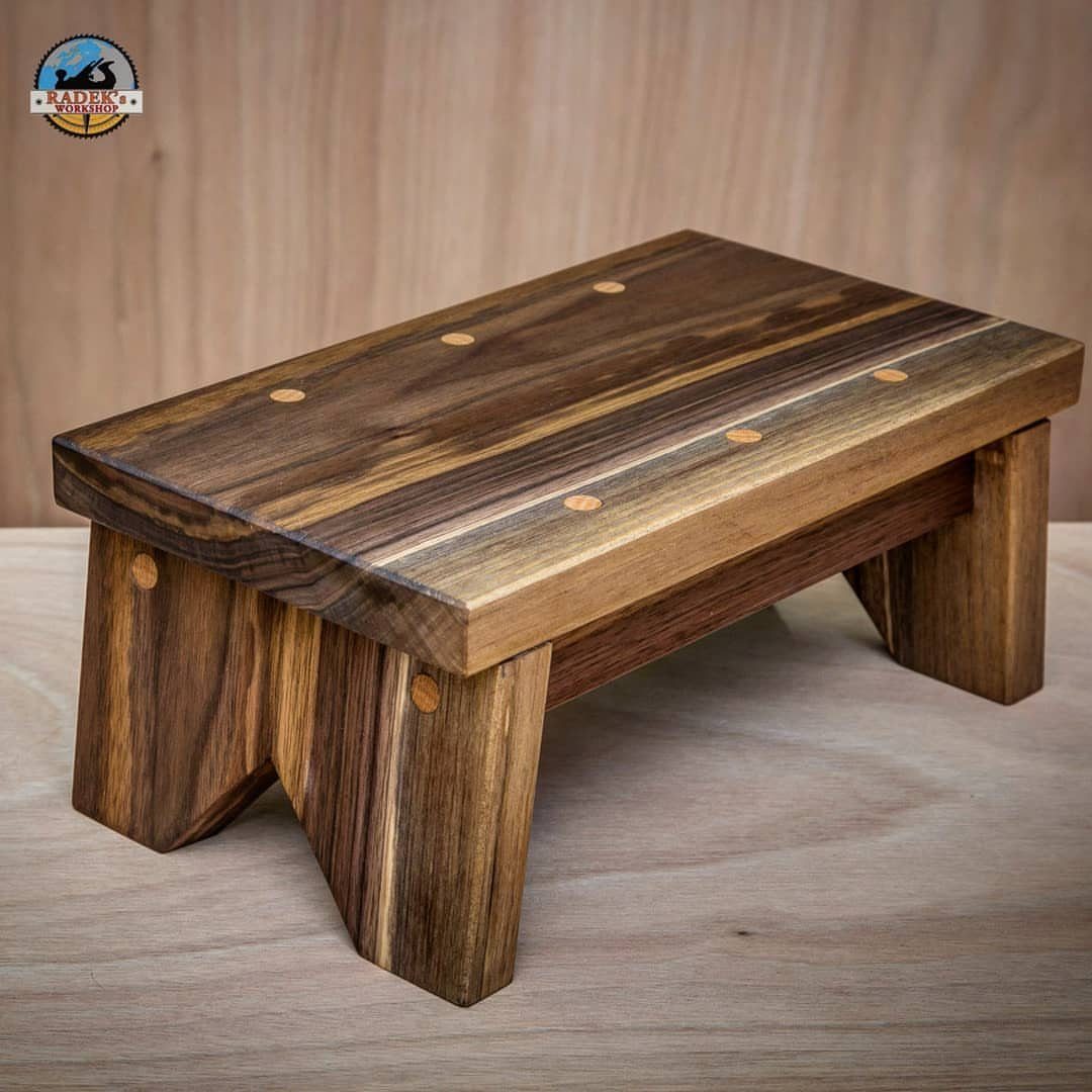 Wooden step stool with dark brown grain and thick legs on a wooden surface.
