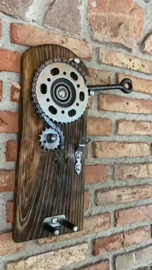 Wall mounted bottle opener made from a wooden board and bicycle gears.