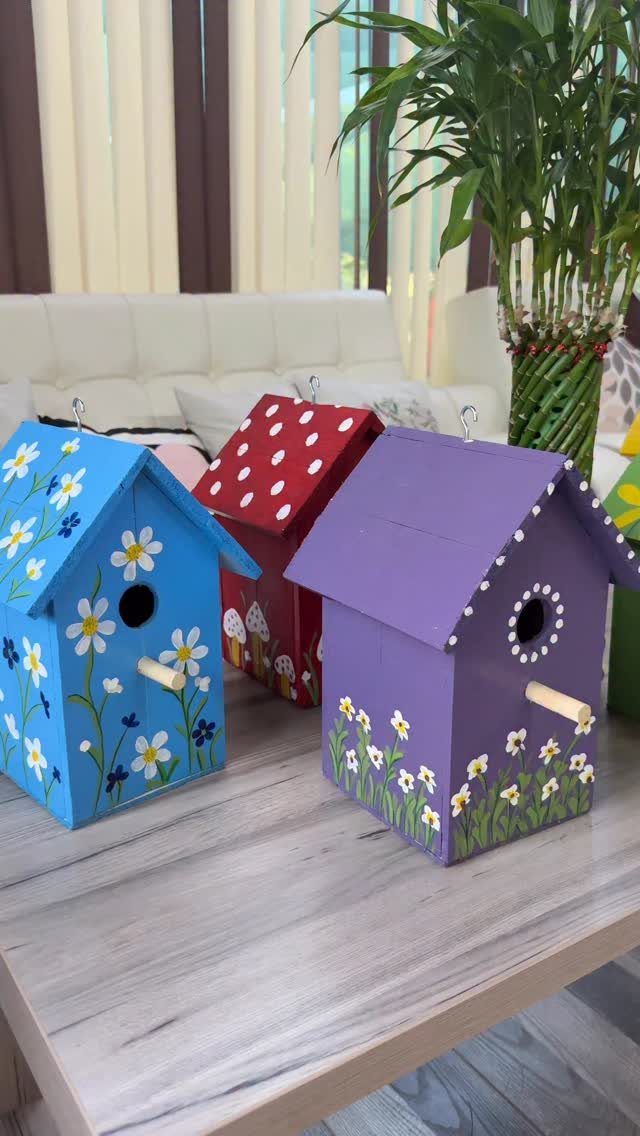 12 Woodworking Ideas to Make Money With Simple Builds 7 Three colorful painted wooden birdhouses with floral and polka dot designs on a table.