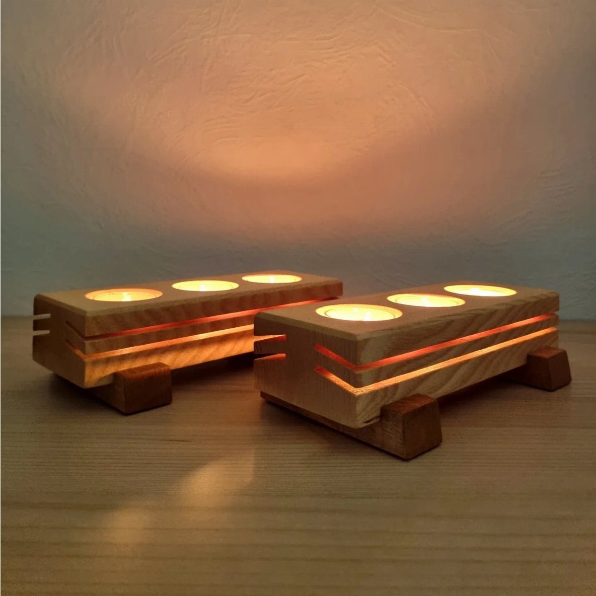 12 Woodworking Ideas to Make Money With Simple Builds 5 Two wooden candle holders with glowing tea light candles on a wooden table.
