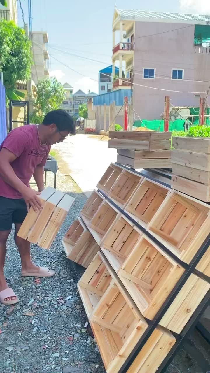 12 Woodworking Ideas to Make Money With Simple Builds 2 Man holding a handmade wooden storage crate next to a stack of crates.