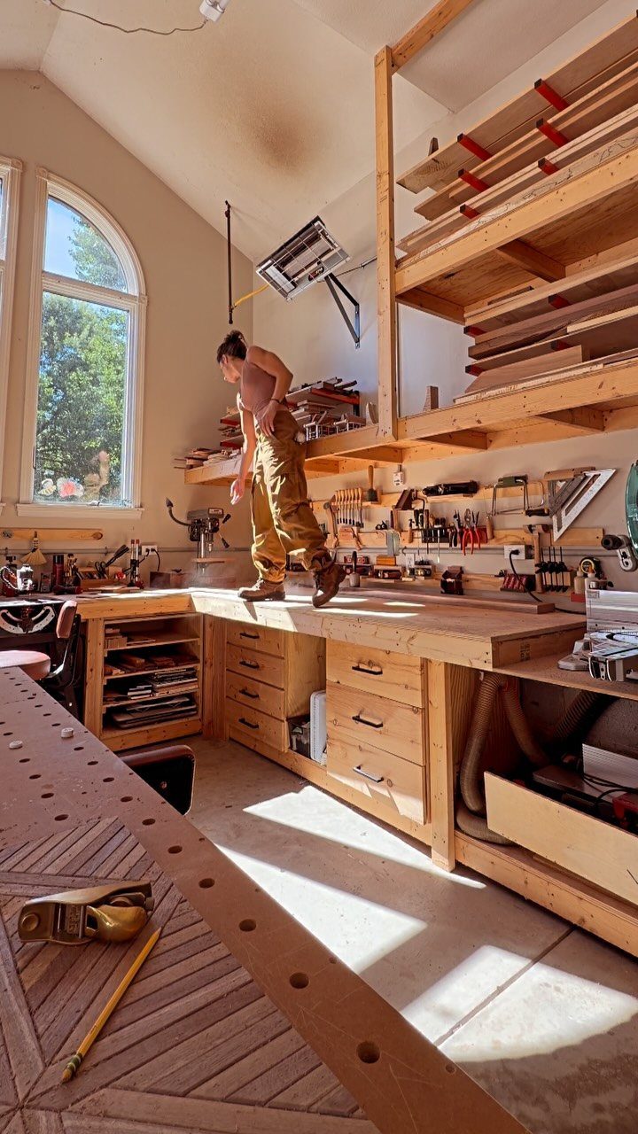 Woodworking Shop Furniture: 4 Ideas for Your Workspace 1 Wooden workbench and built-in storage shelving in a bright, sunlit woodworking shop.