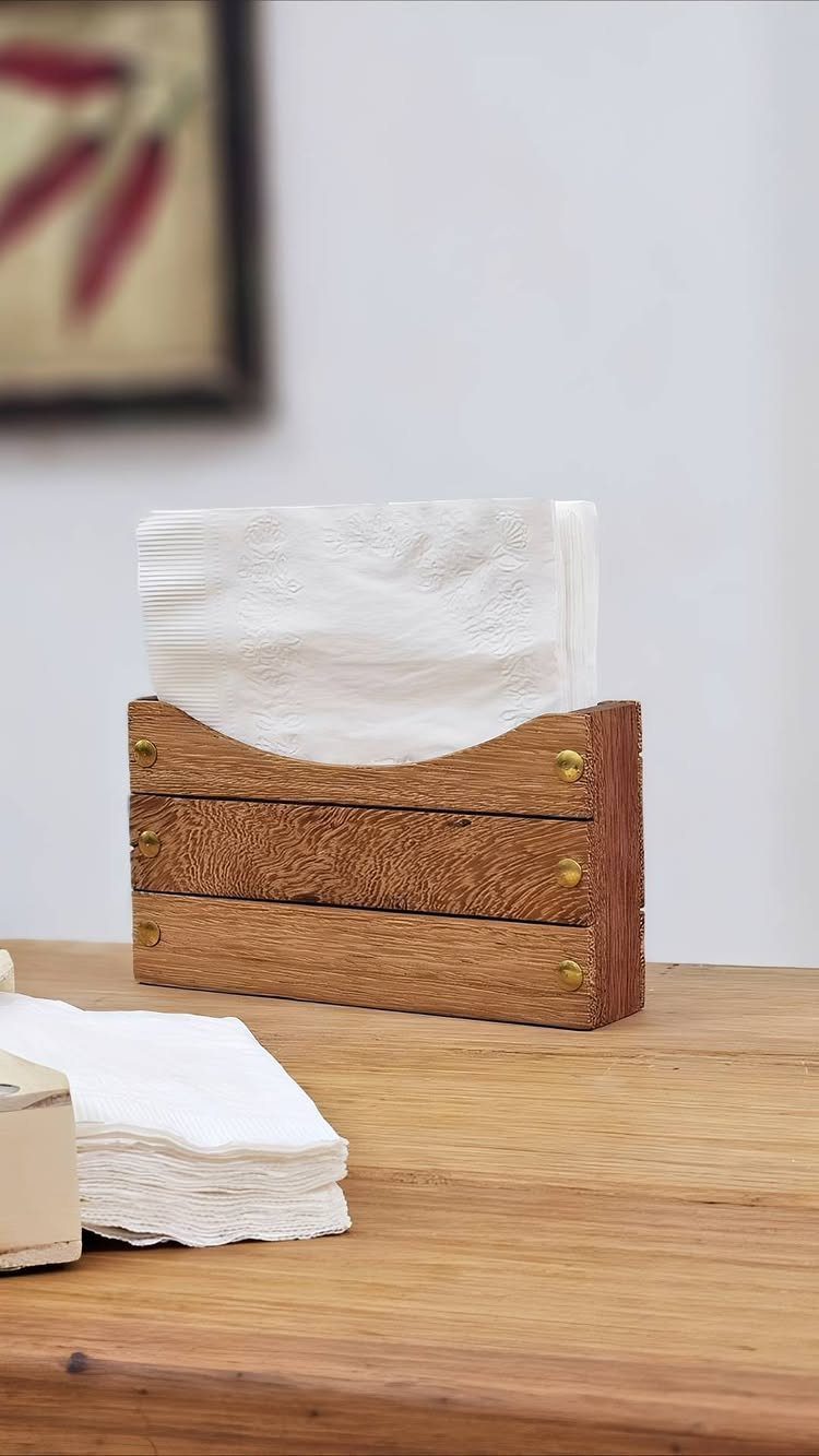 14 Woodworking Shop Projects for Every Skill Level 11 Wooden napkin holder with gold fasteners holding white napkins on a wooden table.