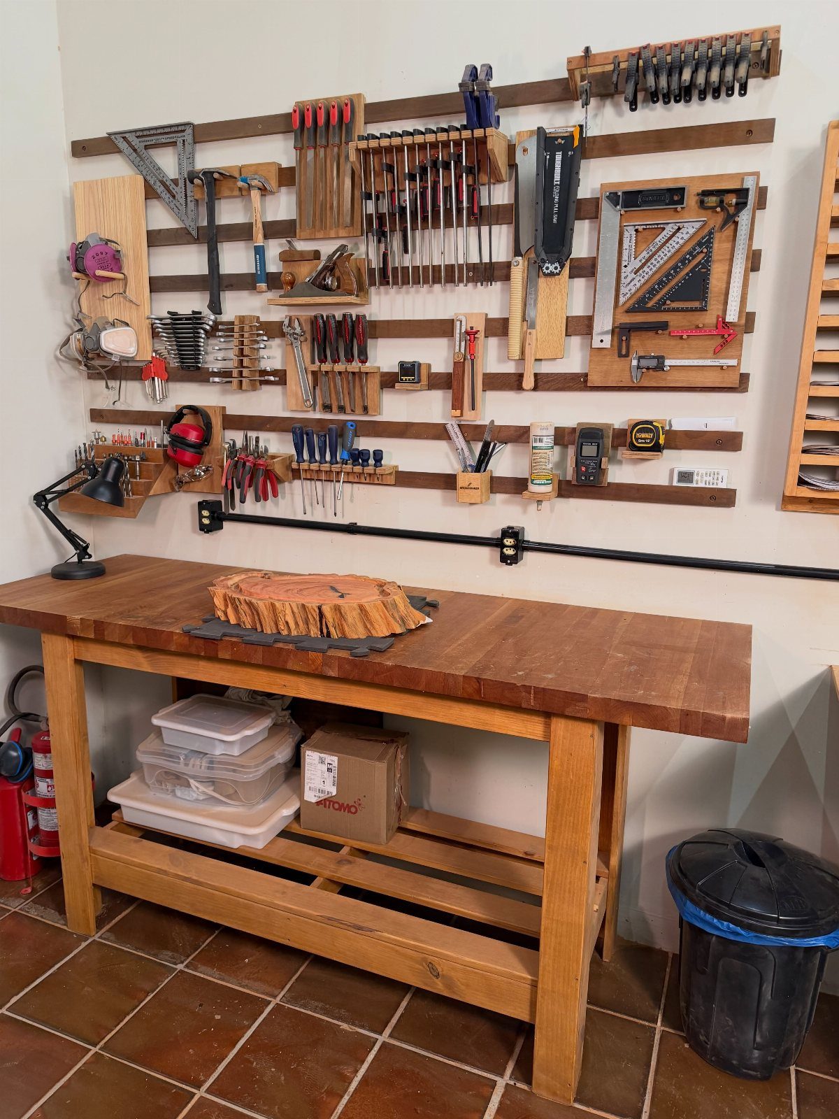 Workbench Tool Storage Ideas: 8 Setups for a Garage Shop 6 Wooden workbench with a wall-mounted tool storage system holding various woodworking hand tools.