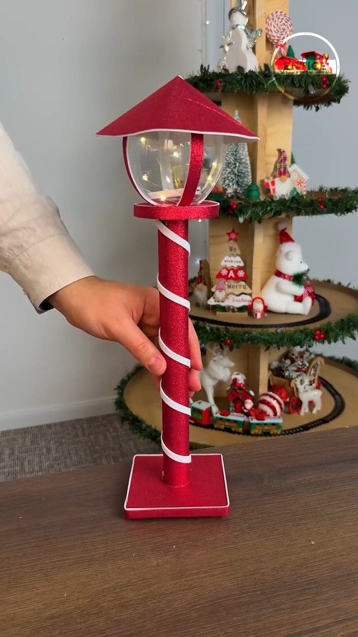 Red glittery lamp post Christmas craft held in front of a tiered display.