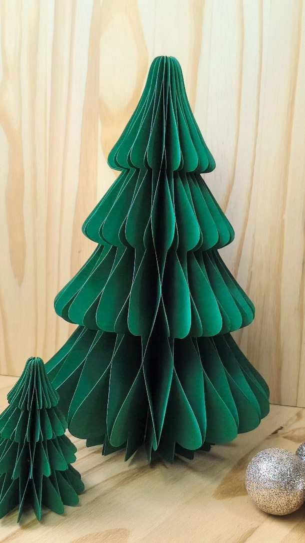 Green paper Christmas trees made from folded cardstock on a light wooden surface.