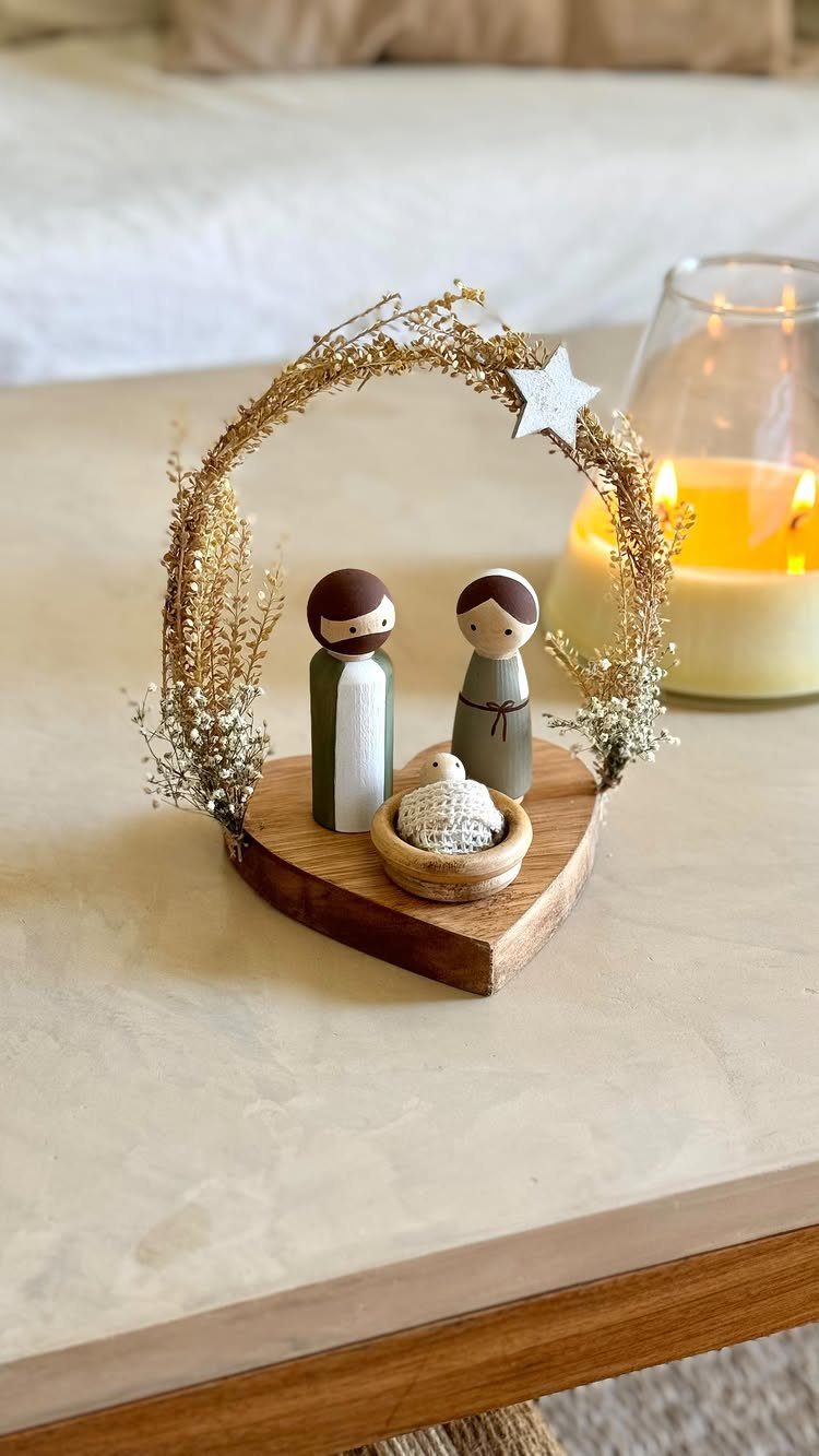 Wooden nativity scene with stylized figures under a golden wire arch and star.